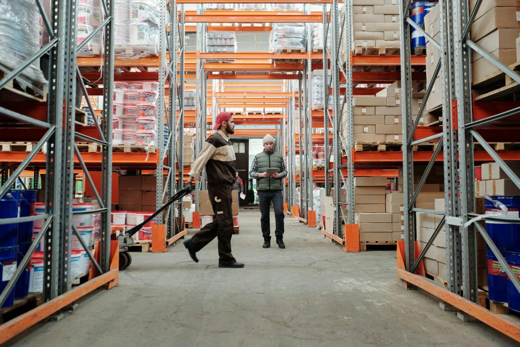 pexels photo 4487365 4487365 Two workers manage inventory in a spacious warehouse aisle.