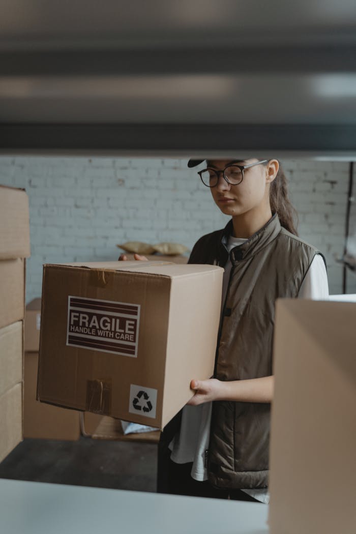 About Female courier handling a fragile package in a warehouse setting.